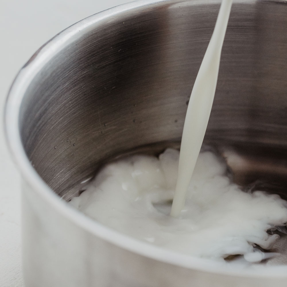 Milch wird in einen Topf mit Wasser gegeben